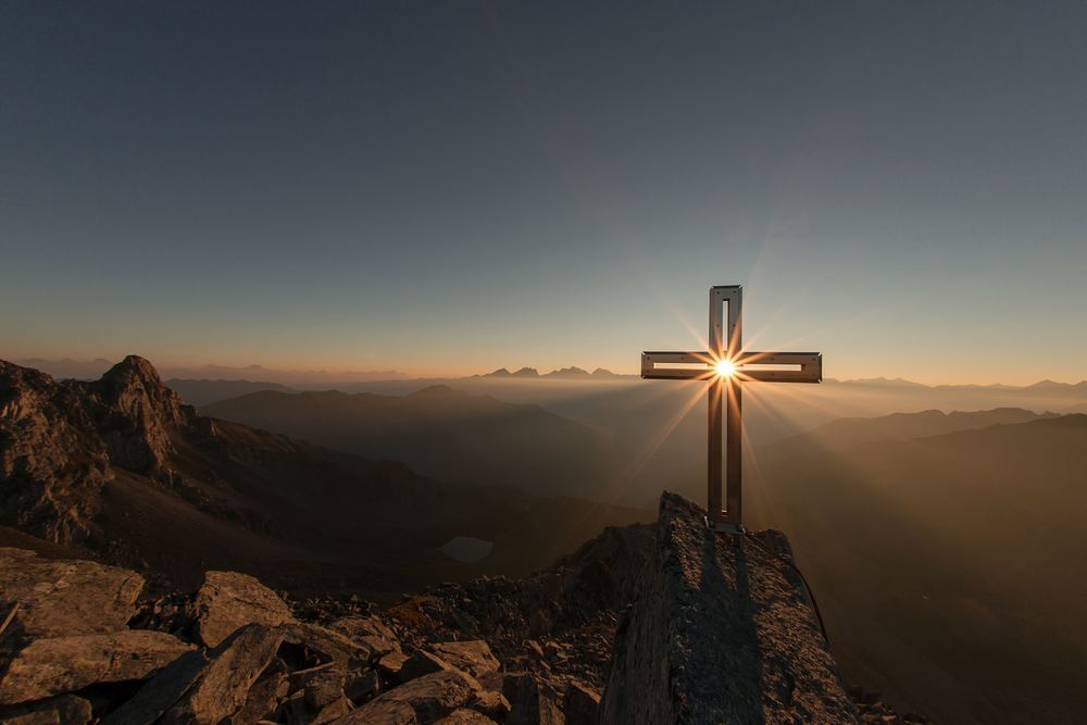 Ostern / Photo by eberhard grossgasteiger on Unsplash / CC0 License Kreuz auf einem Berggipfel im Gegenlicht