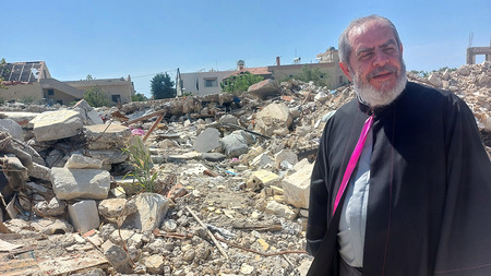 Priester vor zerstörtem Gebäude in Alma Sha'b